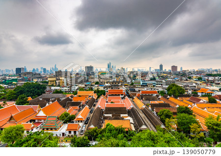 Panorama view of Bangkok city, Thailand. Cityscape of residental buildings in foreground, temples, skyscrapers and modern buildings in far. Fresh trees and plants. Cloudy weather, dramatic clouds. 139050779