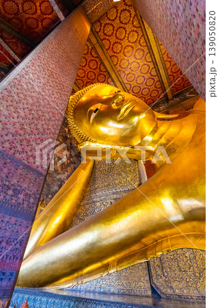 Beautiful statue of reclining golden Buddha placed in Wat Pho temple, Bangkok. Spiritual place of buddhism religion with beautiful ornaments on the pillar. Detail view of Buddha's head 139050820