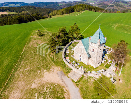 Aerial view of St Michael chapel in czech republic. Chapel is one of the oldest church in country. Fresh agriculture land with small village in background. Beautiful stone religion building, heritage. Aerial view of St Michael chapel in czech republic. Chapel is one of the oldest church in country. Fresh agriculture land with small village in background. Beautiful stone religion building, heritage. 139050958
