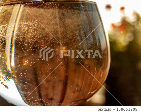 Macro of a glass of water with caustics and bubbles shot on the lumen. High-contrast backlighting highlights optical refraction, air spheres and liquid purity in a radiant clear composition 139051209