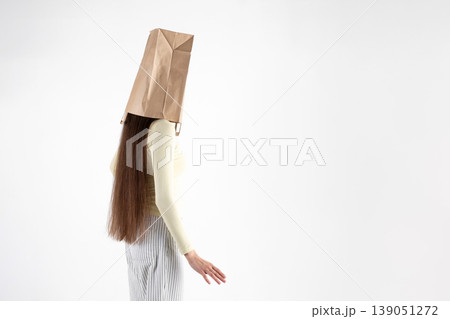 Woman hiding head with paper bag on white background 139051272