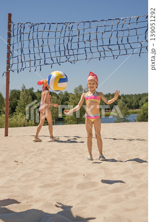 Children play beach volleyball at a school summer camp by the lake.  Sports education 139051292