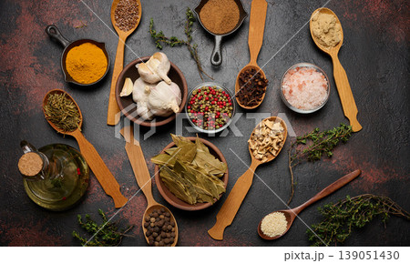 Various ground spices in wooden spoons, olive oil on dark table 139051430