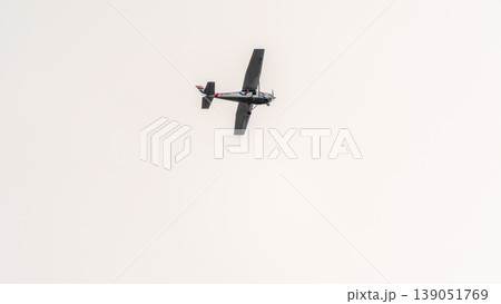 Small ultralight airplane with overhead wing and single propeller flying in sunset sky. 139051769