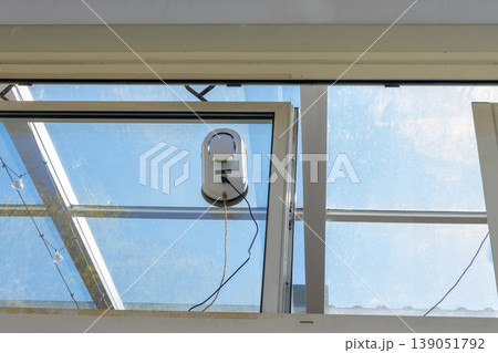 Automatic robot cleans glass window surface against blue sky background Automatic robot cleans glass window surface against blue sky background 139051792