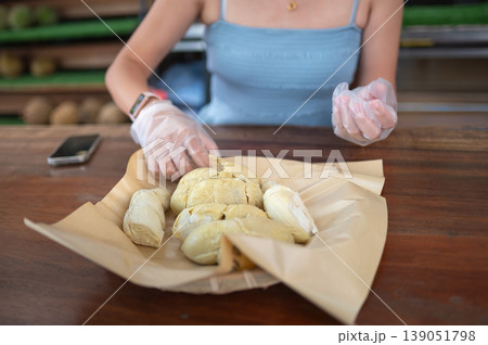 Woman Enjoying Fresh Durian at Local Market with Protective Gloves 139051798