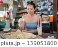Woman Enjoying Durian at a Vibrant Market Buffet with Refreshing Drink 139051800