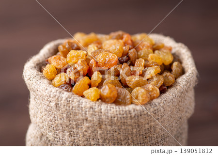 Small bag made of linen fiber full of raisins. Close up shot of sweet tasty raisins in bag 139051812
