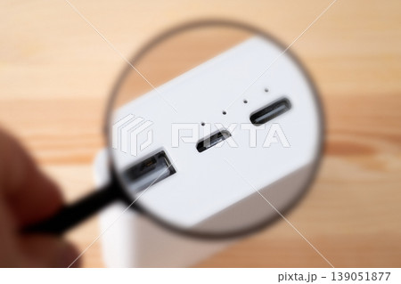 Magnifying glass on Micro USB port on power bank. Using micro usb port for charging gadgets concept Magnifying glass on Micro USB port on power bank. Using micro usb port for charging gadgets concept 139051877