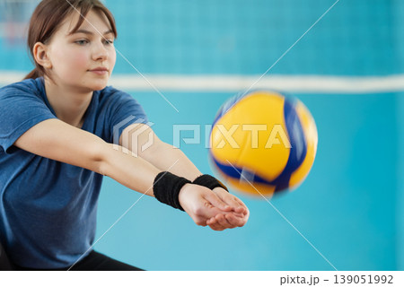 Photo in action of a girl playing volleyball. Young female mastering volleyball skills on volleyball court Photo in action of a girl playing volleyball. Young female mastering volleyball skills on volleyball court 139051992