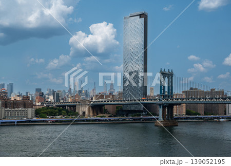 New york, usa august 15,2024. Manhattan bridge spanning the east river with one manhattan square and manhattan skyline towering over brooklyn waterfront, sunny day New york, usa august 15,2024. Manhattan bridge spanning the east river with one manhattan square and manhattan skyline towering over brooklyn waterfront, sunny day 139052195