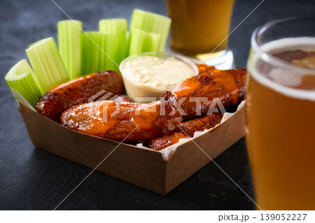 Spicy Buffalo chicken wings with blue cheese sauce and beer in a paper tray on a dark table. crunchy buffalo chicken wings with beer and blue cheese dipping sauce on a dark table. 139052227
