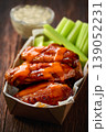 Spicy Buffalo wings with blue cheese sauce and celery sticks in paper tray on a wooden table. crunchy buffalo chicken wings with celery sticks and blue cheese dipping sauce on a wooden table. 139052231