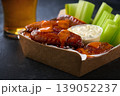 Spicy Buffalo chicken wings with blue cheese sauce and beer in a paper tray on a dark table. crunchy buffalo chicken wings with beer and blue cheese dipping sauce on a dark table. 139052237