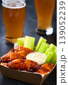 Spicy Buffalo chicken wings with blue cheese sauce and beer in a paper tray on a dark table. crunchy buffalo chicken wings with beer and blue cheese dipping sauce on a dark table. 139052239