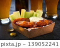 Spicy Buffalo chicken wings with blue cheese sauce and beer in a paper tray on a dark table. crunchy buffalo chicken wings with beer and blue cheese dipping sauce on a dark table. 139052241