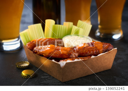 Spicy Buffalo chicken wings with blue cheese sauce and beer in a paper tray on a dark table. crunchy buffalo chicken wings with beer and blue cheese dipping sauce on a dark table. Spicy Buffalo chicken wings with blue cheese sauce and beer in a paper tray on a dark table. crunchy buffalo chicken wings with beer and blue cheese dipping sauce on a dark table. 139052241