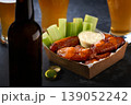 Spicy Buffalo chicken wings with blue cheese sauce and beer in a paper tray on a dark table. crunchy buffalo chicken wings with beer and blue cheese dipping sauce on a dark table. 139052242