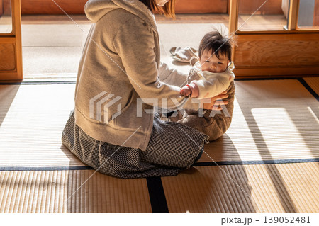 お座りした赤ちゃんを支える母親 139052481