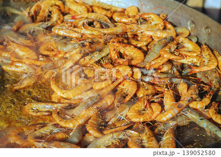 Shrimp cooking in large pan during outdoor picnic barbecue, seafood cooking scene, fresh shrimp frying in oil. Seafood cooking, outdoor food preparation, shrimp meal, street food cooking Shrimp cooking in large pan during outdoor picnic barbecue, seafood cooking scene, fresh shrimp frying in oil. Seafood cooking, outdoor food preparation, shrimp meal, street food cooking 139052580