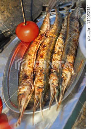 Grilled garfish from Black Sea served whole on metal tray, charred skin prepared in outdoor street food setting in Bulgaria. Seafood cooking, grilled garfish, Black Sea cuisine, street food culture Grilled garfish from Black Sea served whole on metal tray, charred skin prepared in outdoor street food setting in Bulgaria. Seafood cooking, grilled garfish, Black Sea cuisine, street food culture 139052584
