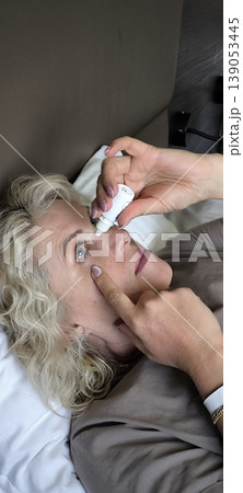 A woman puts drops in her own eyes A woman puts drops in her own eyes 139053445