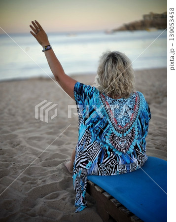 Woman in tunic watching sunset by the sea 139053458