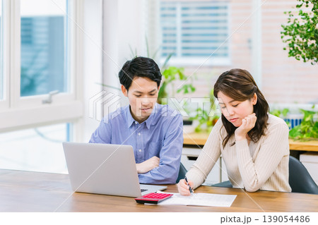 家計簿を書きながら悩む若い夫婦 139054486