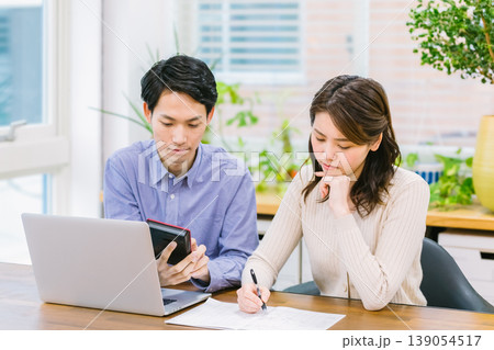 家計簿を書きながら悩む若い夫婦 139054517