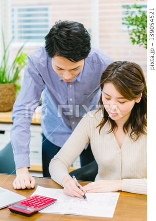 家計簿を書きながら悩む若い夫婦 家計簿を書きながら悩む若い夫婦 139054521