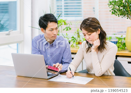 家計簿を書きながら悩む若い夫婦 139054523