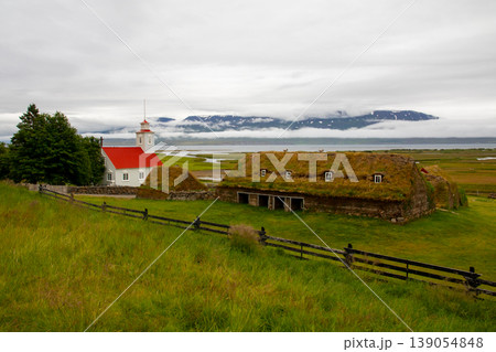 北欧の島国アイスランド　アークレイリ近郊のロイヴァゥス　伝統家屋の芝屋根のターフハウスと教会 139054848