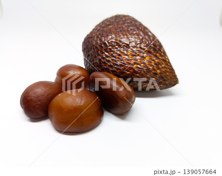 Front view of an empty scaly snake fruit shell and several smooth brown seeds, isolated on a white background. Front view of an empty scaly snake fruit shell and several smooth brown seeds, isolated on a white background. 139057664