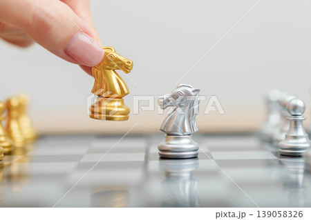 hand moving gold Chess knight figure and Checkmate opponent during chessboard competition. Strategy, Success, management, business planning, win, disruption, Trade war and leadership concept hand moving gold Chess knight figure and Checkmate opponent during chessboard competition. Strategy, Success, management, business planning, win, disruption, Trade war and leadership concept 139058326