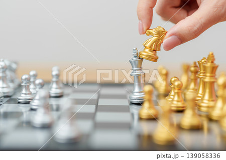 hand moving gold Chess knight figure and Checkmate opponent during chessboard competition. Strategy, Success, management, business planning, win, disruption, Trade war and leadership concept hand moving gold Chess knight figure and Checkmate opponent during chessboard competition. Strategy, Success, management, business planning, win, disruption, Trade war and leadership concept 139058336