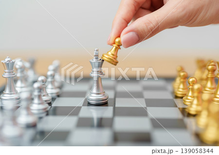 hand moving gold Chess Pawn figure and Checkmate opponent during chessboard competition. Strategy, Success, management, business planning, win, disruption, Trade war and leadership concept 139058344