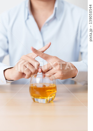 Man making stop hand gesture to refuse a glass of whiskey, Healthy man say no to alcohol drink, stop alcoholism and addiction concept. Responsible man reject a drink before driving and quit booze 139058544