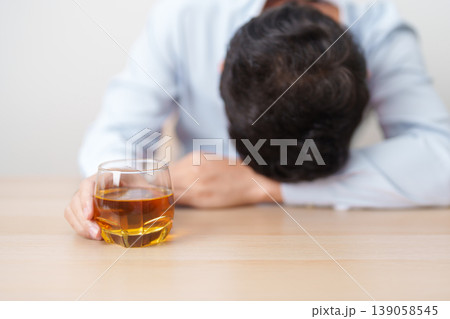 Stressed man drinking cognac alone with problem. Exhausted drunk man looking stressed and sleepy. Alcohol addiction, Alcoholism, emotional distress and mental health concept 139058545