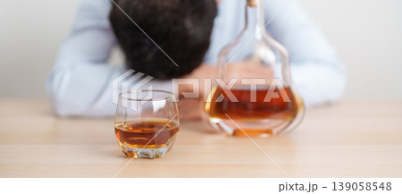 Stressed man drinking cognac alone with problem. Exhausted drunk man looking stressed and sleepy. Alcohol addiction, Alcoholism, emotional distress and mental health concept Stressed man drinking cognac alone with problem. Exhausted drunk man looking stressed and sleepy. Alcohol addiction, Alcoholism, emotional distress and mental health concept 139058548