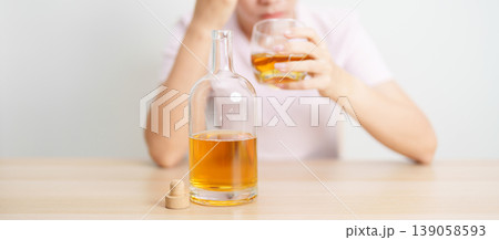 Stressed woman drinking whisky alone with problem. Exhausted drunk man looking stressed and sleepy. Alcohol addiction, Alcoholism, emotional distress and mental health concept 139058593