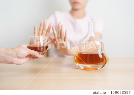 woman making stop hand gesture to refuse a glass of Cognac, Healthy man say no to alcohol drink, stop alcoholism and addiction concept. Responsible man reject a drink before driving and quit booze 139058597