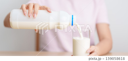 Healthy woman pouring fresh milk into glass at home, female drinking for calcium and strong bones, high protein, dairy product for healthy lifestyle, wellness and daily routine concept Healthy woman pouring fresh milk into glass at home, female drinking for calcium and strong bones, high protein, dairy product for healthy lifestyle, wellness and daily routine concept 139058618