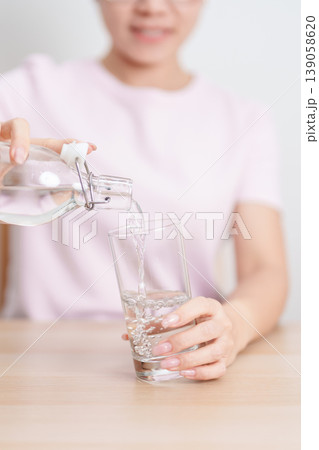 Healthy woman pour clean mineral water into glass at home, female drink pure water for hydration and wellness, fresh skin care, daily routine water intake, Refreshment and lifestyle concept Healthy woman pour clean mineral water into glass at home, female drink pure water for hydration and wellness, fresh skin care, daily routine water intake, Refreshment and lifestyle concept 139058620