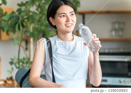 自宅トレーニング後にペットボトルのミネラルウォーターで水分補給をするアジア人女性 自宅トレーニング後にペットボトルのミネラルウォーターで水分補給をするアジア人女性 139058983