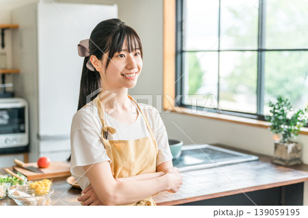 キッチンの前で腕組みするエプロン姿の若いアジア人女性 キッチンの前で腕組みするエプロン姿の若いアジア人女性 139059195