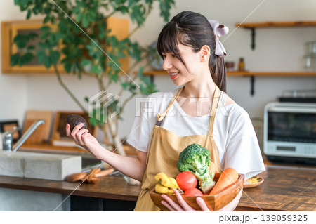 キッチンで野菜,アボカドを持つエプロン姿の若いアジア人女性 キッチンで野菜,アボカドを持つエプロン姿の若いアジア人女性 139059325