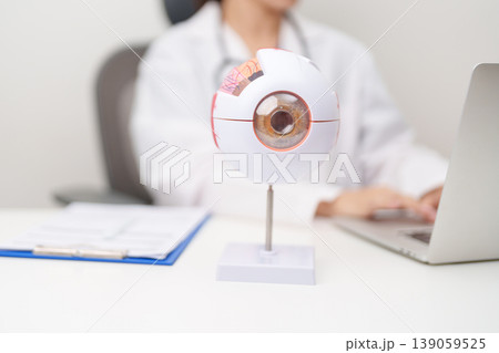 Doctor with human Eye anatomy model with magnifying glass. Eye disease, Refractive Errors, Age Related Macular Degeneration, Cataract, Diabetic Retinopathy, Glaucoma, Amblyopia, Strabismus and Health 139059525