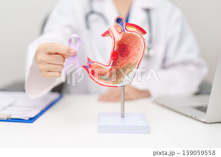 Doctor with Gastric anatomy model and Purple ribbon. November stomach cancer Awareness month, Gastroenterologist consultation, stomach diseases and ulcers, Gastroesophageal Reflux and Acid reflux Doctor with Gastric anatomy model and Purple ribbon. November stomach cancer Awareness month, Gastroenterologist consultation, stomach diseases and ulcers, Gastroesophageal Reflux and Acid reflux 139059558