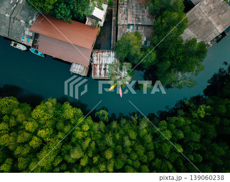 Top-down aerial view of a riverside fishing village and mangrove forest with kayaks. 139060238