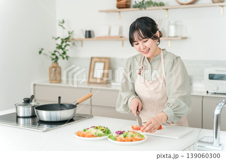 キッチンで料理をするエプロン姿の若いアジア人女性 139060300